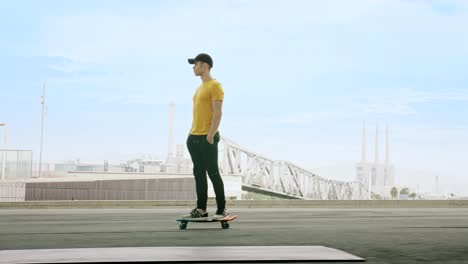 lateral-view-of-a-Young-Attractive-Trendy-Man-skateboarding-fast-under-a-solar-panel-on-a-morning-sunny-day-with-an-urban-city-background