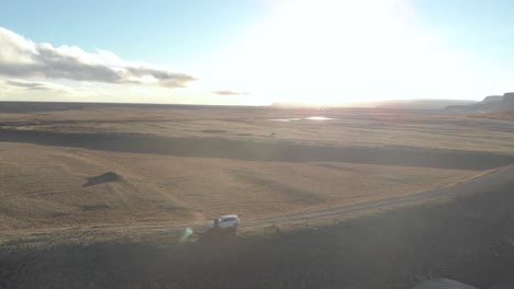 Aerial-Orbital-Shot-of-a-Lone-Car-Parked-in-a-Vast-Landscape