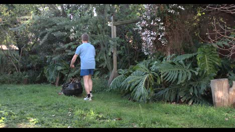 Man-mowing-the-lawn-in-a-garden-going-backwards-and-forwards-4k-footage