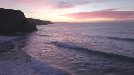 Eine-Klippe-Sitzt-Als-Silhouette,-Wenn-Die-Sonne-Untergeht-Und-Die-Brandung-Im-Ozean-In-Cornwall-Spielt