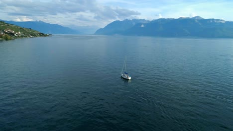 Aerial-orbit-around-sailboat-on-Lake-Leman-in-front-of-Villette,-Lavaux---Switzerland