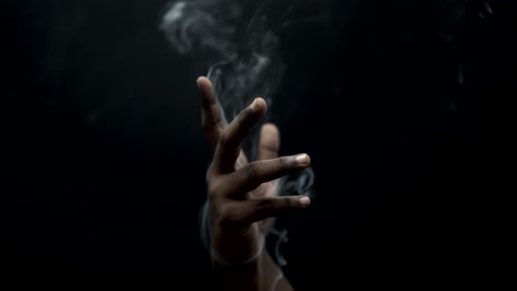 smoke-coms-in-hand-in-background-black-closeup-view