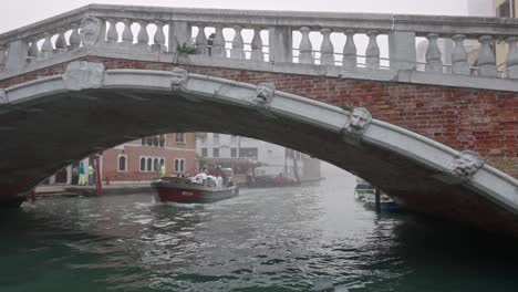 Slow-motion-from-a-boat-in-a-canal-passing-under-a-bridge-in-Venice-Italy