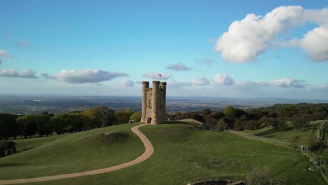 Low-aerial-shot-orbiting-Broadway-tower,-an-English-landmark-stood-atop-Beacon-Hill-in-the-Cotswolds,-UK