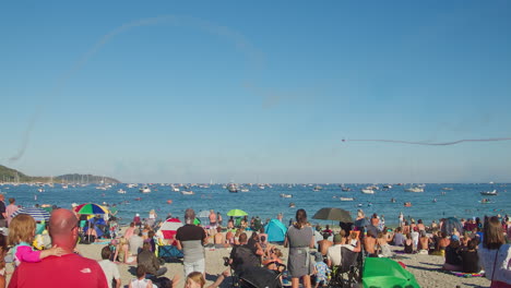 People-At-The-Beach-Stunned-By-Aerobatics-Display-Of-RAF-Red-Arrows-During-Falmouth-Week-In-The-UK