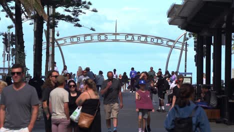 Popular-tourist-hotspot,-busy-downtown-Gold-coast-city-crowded-with-people-strolling-on-Cavill-avenue-with-surfers-paradise-sign-in-the-background-at-the-esplanade,-Queensland,-Australia