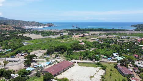 Aerial-drone-view-of-rural-countryside-landscape,-ocean-views-over-port-infrastructure-development-and-traveling-traffic-in-Tibar,-Timor-Leste,-Southeast-Asia