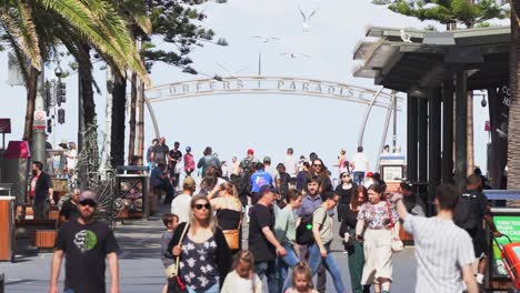 Static-shot-at-tourist-hotspot,-busy-downtown-Gold-coast-city-crowded-with-people-strolling-on-Cavill-avenue-with-surfers-paradise-sign-in-the-background-at-the-esplanade,-Queensland,-Australia