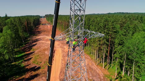 Aerial-drone-rotating-shot-over-a-electric-pole-been-installed-by-a-group-of-electrical-technicians-on-a-bright-sunny-day