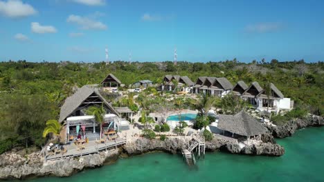 Beach-bungalow-resort-with-pool-and-people-relaxing,-Aerial-rising-pedestal-shot