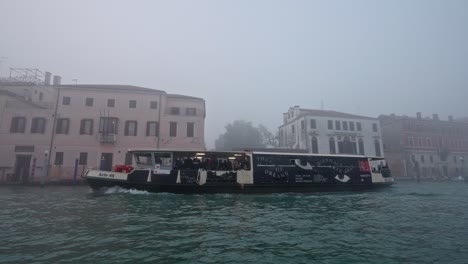 Slow-motion-from-Canal-Grande-of-ferry-boat-in-Venice-Italy,-with-spot-of-the-Biennale-of-Art