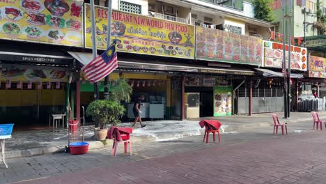 Trabajador-Limpia-El-Piso-Y-Se-Prepara-Para-Los-Negocios-En-Jalan-Alor-Food-Street,-Kuala-Lumpur,-Malasia