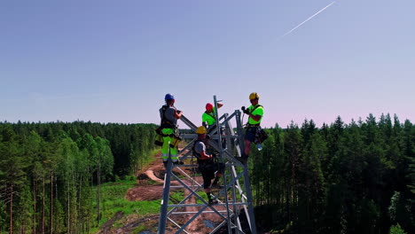Aerial-close-up-shot-of-workers-climbing-on-transmission-tower-for-build-new-modern-in-woodland