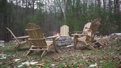 Wide-view-of-six-empty-outdoor-chairs-around-a-burning-fire-pit