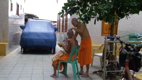 One-Monk-Cutting-Another-Monk's-Hair-in-Back-Ally-in-Bangkok-Thailand