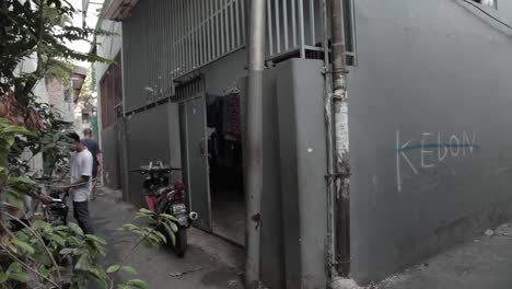 Asian-looking-man-carries-plastic-bag-in-an-alley,-somewhere-in-Jakarta