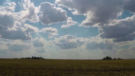 Riesiges-Grünes-Feld-Mit-Kleinen-Baumgruppen-In-Der-Ferne-An-Einem-Blauen-Sonnigen-Tag-Mit-Vielen-Wolken-Am-Himmel