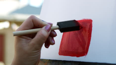 SLOW-MOTION-video-of-female-artist-hand-wearing-pink-nail-varnish-applying-red-paint-to-canvas-using-sponge-brush