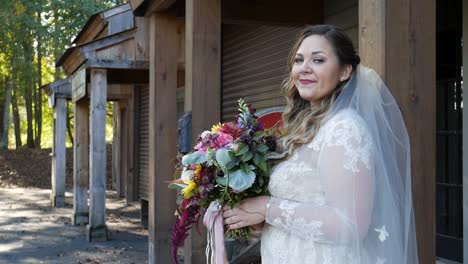 Atlanta,-GA---November-21,-2018:-A-millennial-bride-poses-wearing-her-wedding-dress-and-holding-flowers-during-golden-hour-before-her-wedding-at-a-rustic-rural-country-farm-venue