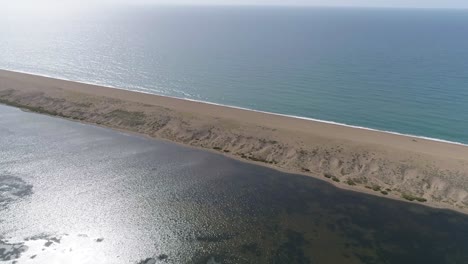 Aerial-tracking-top-down-over-the-fleet-near-abbotsbury,-camera-pans-up-to-reveal-chesil-beach-and-the-horizon-along-the-english-channel