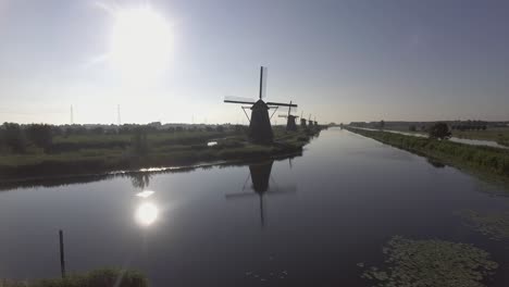 A-drone-shot-panning-backwards,-around-Dutch-Windmills-during-sunrise