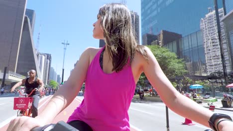 Beautiful-young-brunette-woman-on-bicycle-standing-on-the-bike-path-of-Paulista-Avenue-on-a-beautiful-sunny-day