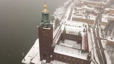 Zoom-out-tilting-aerial-footage-over-iconic-Stockholm's-town-hall-during-winter-storm