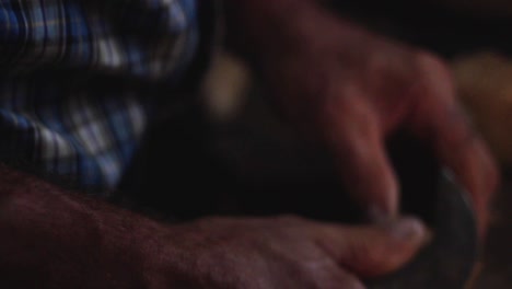 close-up-of-country-man's-hands-working-with-wood-in-his-old-workroom-on-a-wooden-workplace-at-night-with-a-smooth-warm-light