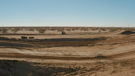 Slow-motion-aerial-view-of-motocross-biker-racing-on-dirt-track-in-Mojave-Desert
