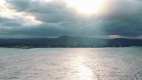 Time-lapse-view-departing-Kingston,-Jamaica-at-sunset-on-a-cloudy-summer-evening
