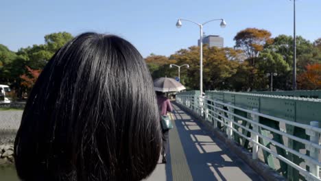 Following-shot-of-people-walking-over-bridge-towards-peace-park-islands-in-Hiroshima
