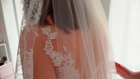 Two-women-preparing-wedding-lace-veil-for-bride-marriage,-helping-hands-fitting-with-white-dress,-close-up-slowmotion