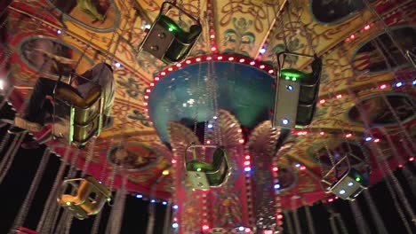 Father-and-daughter-having-fun-in-a-colorful-carousel-at-night-in-a-park-in-slow-motion