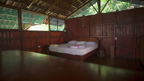 Panning-through-a-beautifully-decorated-but-simple-private-beach-resort-room-with-a-white-linen-bed-and-natural-wood-paneling