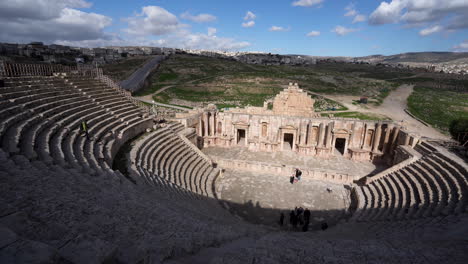 Panoramic-View-of-North-Theater-of-Jerash-in-Roman-Ruins-with-Tourists-Walking-on-the-Stone-Stairs-and-Clouds-Casting-Shadows-on-the-Theater-Plaza
