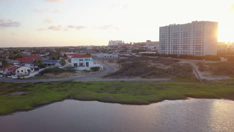 A-natural-lake-reflecting-the-sky-sits-in-front-of-hotels-and-houses-in-Aruba-during-a-beautiful-sunset