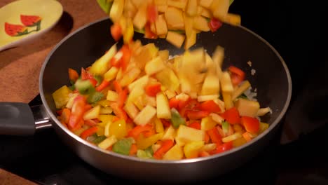 Adding-mixed-chopped-vegetables-into-a-frying-pan-with-browning-onions