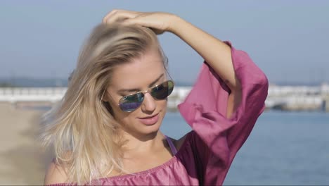 Candid-portrait-of-a-gorgeous-blonde-woman-adjusting-her-hair-at-the-beach