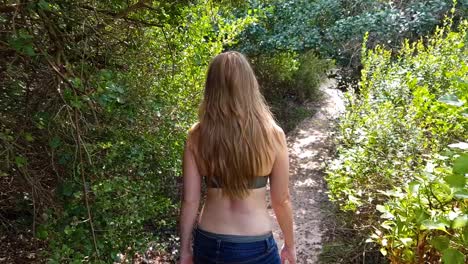 A-woman-walking-through-a-forest-by-the-ocean-with-beautiful-views-in-slow-motion