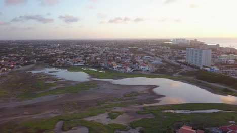 A-natural-lake-reflecting-the-sky-sits-in-front-of-a-neighborhood-in-Aruba