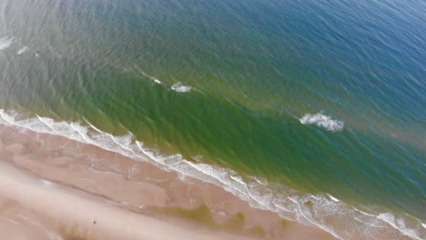 Aerial-view-of-the-North-Sea-shoreline-with-rolling-waves-outside-Løkken,-Denmark