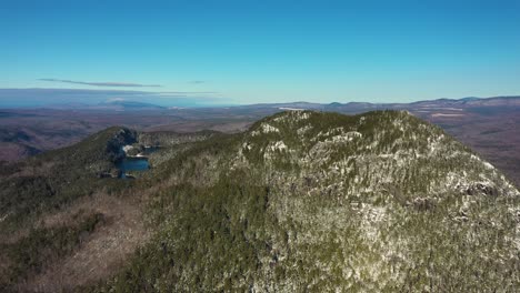 High-aerial-pullback-away-from-snow-dusted-mountain-in-Maine