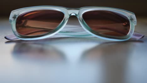 Blue-sunglasses-sitting-on-slightly-reflective-wood-table