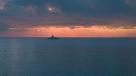 Wide-aerial-view-of-a-Royal-Navy-Warship-sailing-on-a-calm-sea-at-sunrise