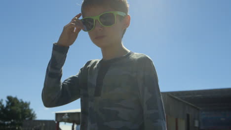 Cooles-Kind-Mit-Grüner-Sonnenbrille-Starrt-Selbstbewusst-In-Die-Kamera