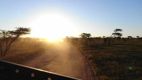 Blick-Auf-Einen-Afrikanischen-Sonnenuntergang-Mit-Blick-Auf-Die-Rückseite-Eines-Safarifahrzeugs-In-Der-Serengeti