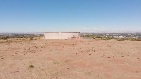 DRONE-Reveal-Shot-of-Water-Supply-Tank-supplying-water-to-a-Town-in-the-Background-on-a-Sunny-Day