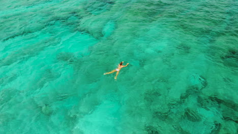 Girl-swimming-in-the-clear-waters-of-the-Bali-Sea-on-a-hot,-sunny-day