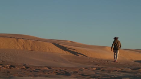 Silhouette-Einer-Figur,-Die-Bei-Sonnenuntergang-Auf-Dem-Sandkamm-Der-Wüste-Spazieren-Geht