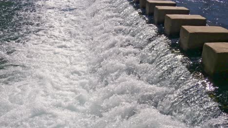 Fast-moving-water-over-a-weir-creating-white-water-rushing-down-stream